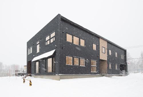 a black building with snow on it in the snow at Hirafu Tomten in Kutchan