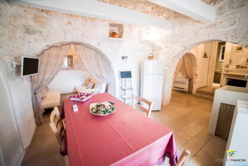 a dining room with a red table and a kitchen at La linea dell'orizzonte in Alberobello
