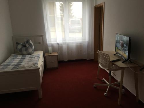 a bedroom with a bed and a desk with a computer at Jimmy Gastronomie & Übernachtung in Altheim