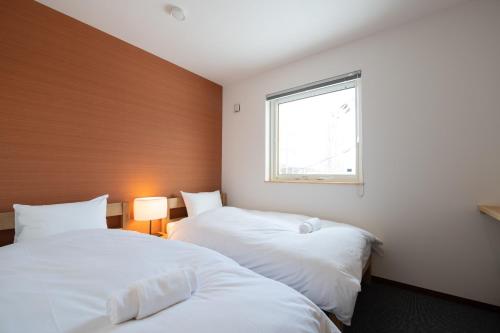 two beds in a room with a window at Hirafu Tomten in Kutchan