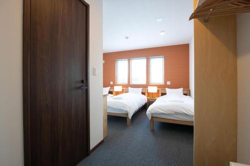a hotel room with two beds and two windows at Hirafu Tomten in Niseko