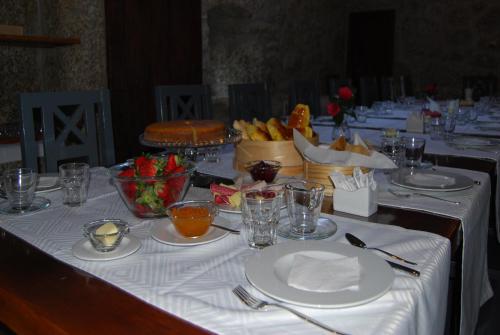 a long table with white plates and bowls of food at Quinta Casa da Fonte in Vieira do Minho