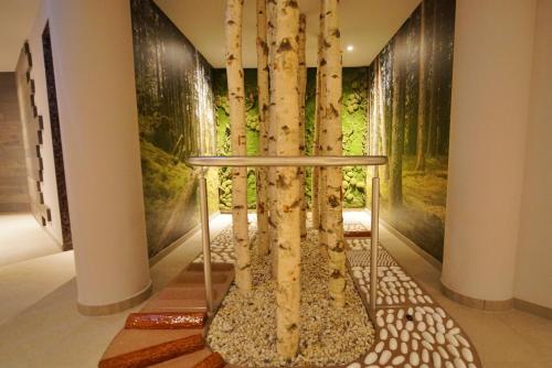 a tree in the middle of a room with paintings at VILA VITA Rosenpark in Marburg an der Lahn
