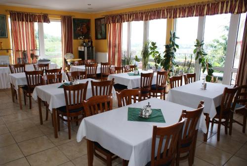 a restaurant with white tables and chairs and windows at Pension Zlata Noha in Bratislava