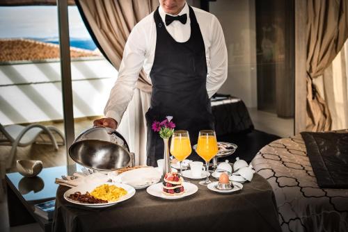 a man standing in a room with a tray of food at Grand Hotel Resort&SPA Ma&Ma - Adults Only in La Maddalena