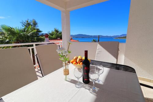 a table with a bottle of wine and a bowl of fruit at Apartments Mediterranean House in Klek