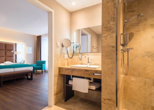 ein Bad mit einer Dusche, einem Waschbecken und einem Spiegel in der Unterkunft Hollywood Media Hotel am Kurfürstendamm in Berlin