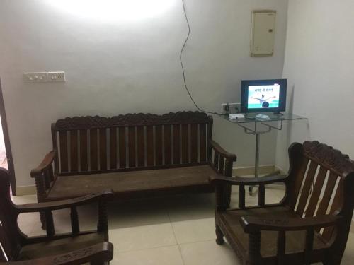 a room with a bench and two chairs and a television at Montecello in Trivandrum