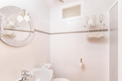 La salle de bains blanche est pourvue d'un miroir et d'un lavabo. dans l'établissement Apartamentos CARABELA BEACH Alcudia, à Alcúdia