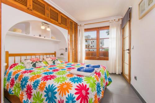 - une chambre avec un lit et une couette colorée dans l'établissement Apartamentos CARABELA BEACH Alcudia, à Alcúdia