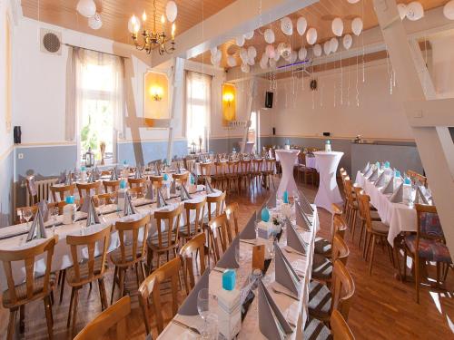 un salón de banquetes con mesas y sillas blancas en Hasseröder Hof, en Wernigerode