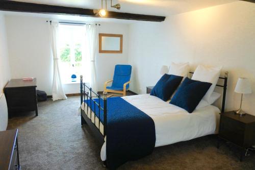 a bedroom with a bed and a blue chair at L'Auberdiere in Saint-Jean-des-Essartiers