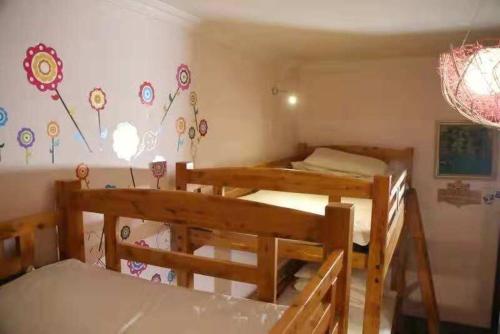 a room with two bunk beds and a wall with flowers at Xi'an The Facebook Youth Hostel in Xi'an