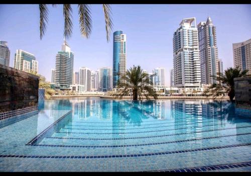 a large swimming pool in a city with tall buildings at 1 BEDROOM APARTMENT in DUBAI MARINA & JBR in Dubai