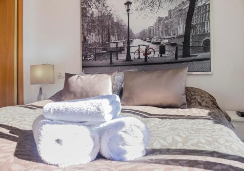 Una cama con toallas blancas encima. en Apartamento S.Quintin, en Málaga