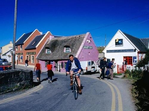mężczyzna jadący rowerem ulicą w obiekcie Elfin Cottage w mieście Doolin