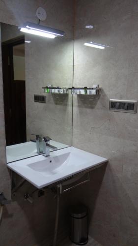 a bathroom with a white sink and a mirror at Arna Hotel in Devanahalli-Bangalore