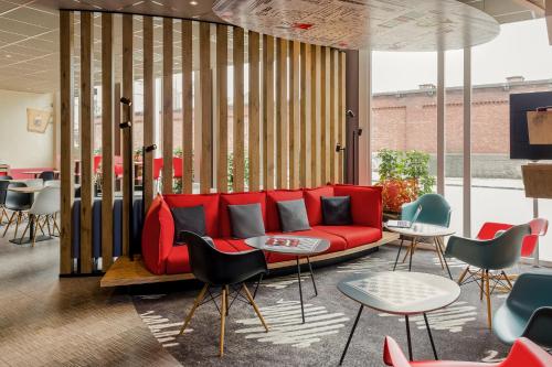 a lobby with a red couch and tables and chairs at ibis Namur Centre in Namur