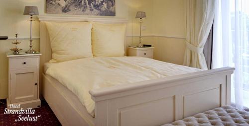 a bedroom with a white bed with two night stands at Strandvilla Seelust in Schönberger Strand
