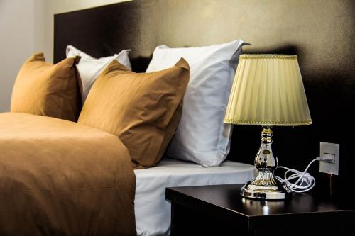 a bed with white pillows and a lamp on a table at Kristal Hotel in Baku
