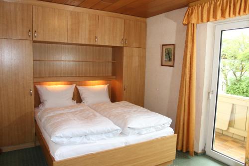 a bedroom with a bed with a wooden headboard and a window at Appartementhaus Moos in Lam