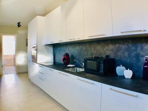 a kitchen with white cabinets and a microwave at Maraini Apartments by Quokka 360 - strategic location near Lugano station in Lugano