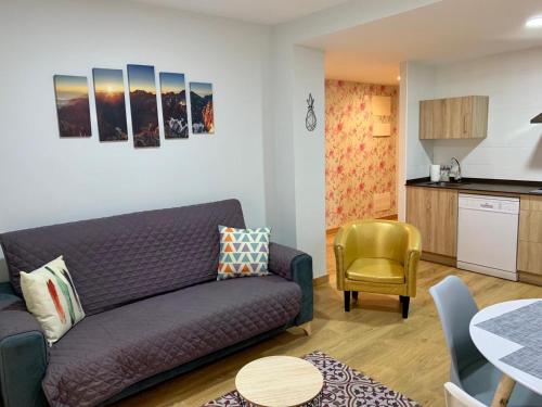 ein Wohnzimmer mit einem lila Sofa und einer Küche in der Unterkunft Apartamentos Maladeta in Benasque