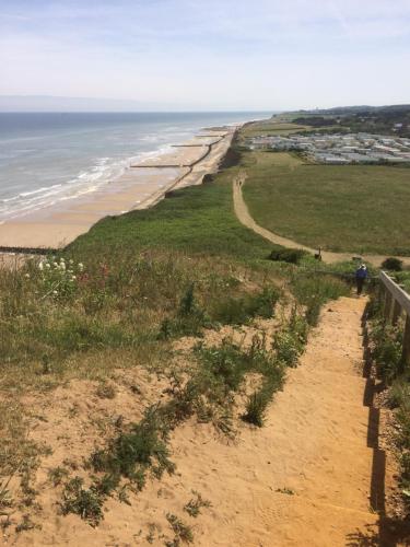 a person walking down a dirt path to the beach at Huge 6 Bedroom House in Sheringham in Sheringham