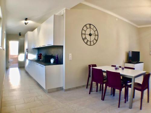 a kitchen and dining room with a table and a clock on the wall at Maraini Apartments by Quokka 360 - strategic location near Lugano station in Lugano