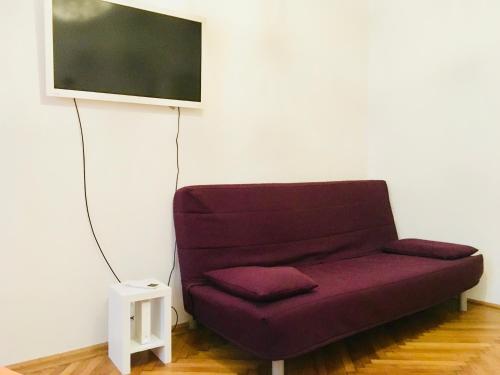a purple couch sitting under a tv on a wall at Apartment opera 1 in Vienna