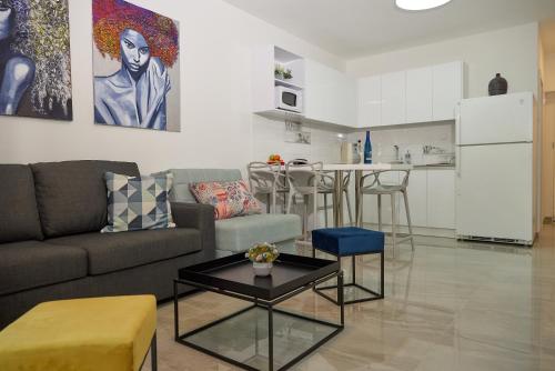 a living room with a couch and a table and a kitchen at דירת גן פונה לבריכה - pool garden view eilat in Eilat