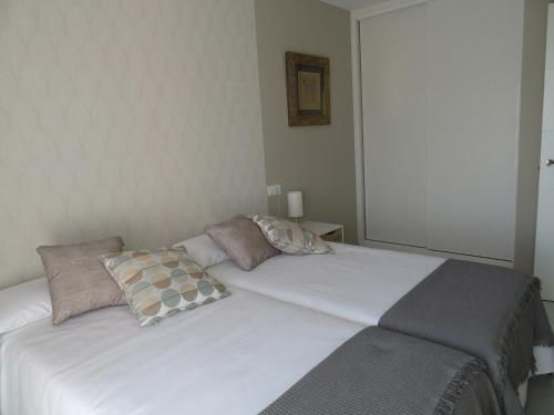 Una cama blanca con dos almohadas encima. en Alcañiz Flats II, en Alcañiz