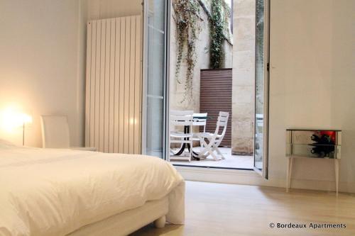 1 Schlafzimmer mit einem Bett und einem Balkon mit einem Tisch in der Unterkunft Bordeaux City Gardens in Bordeaux