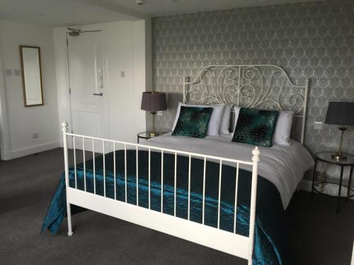 a bedroom with a white bed with green pillows at Lamlash Bay Hotel in Lamlash