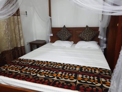 a bedroom with a bed with white sheets and curtains at Abraham Beach House in Tangalle