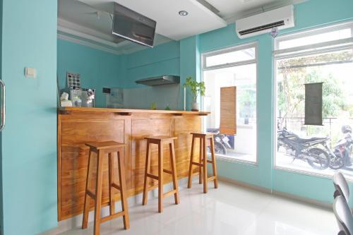 a kitchen with blue walls and a bar with stools at RedDoorz near Solo Balapan Station in Solo