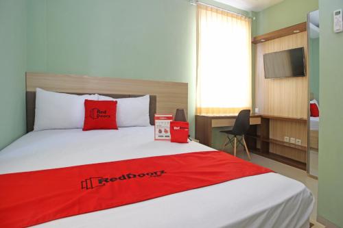 a hotel room with a bed with a red blanket at RedDoorz near Solo Balapan Station in Solo