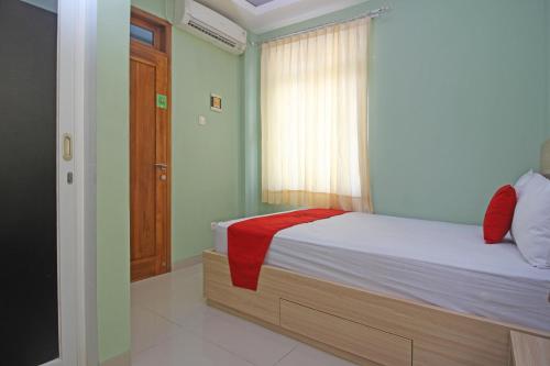 una camera da letto con un letto con una coperta rossa sopra di RedDoorz near Solo Balapan Station a Solo