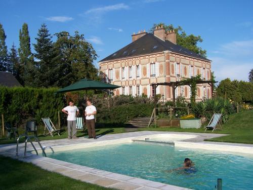 two people standing in a swimming pool in front of a building at Château des Bouffards in Brinon-sur-Sauldre