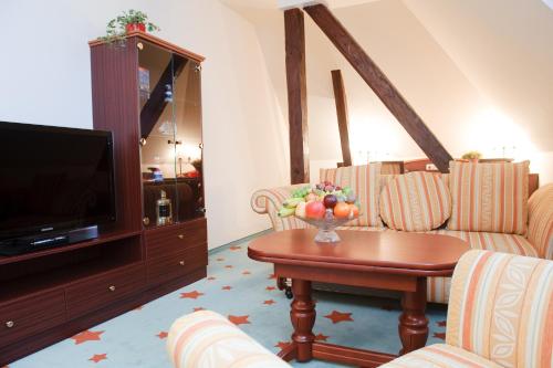 a living room with a table and a television at Stadthotel Stern in Wismar