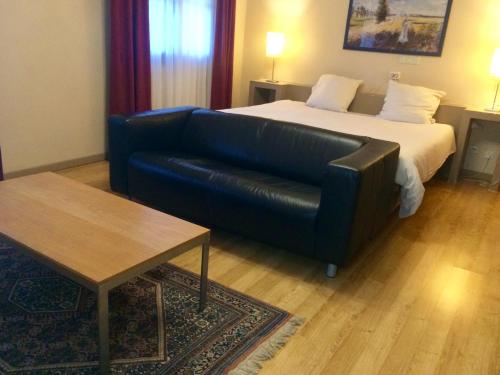 a living room with a couch and a bed at Hotel La Venerie in Virton