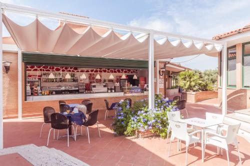 a patio with tables and chairs and a restaurant at Villaggio Mare Si in Follonica