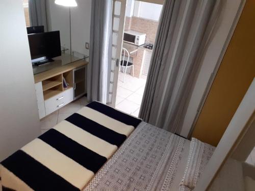 um quarto com uma cama e uma janela com uma televisão em AP Floripa em Florianópolis