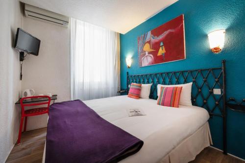a bedroom with a large bed with a blue wall at Hôtel Brimer Cannes in Cannes