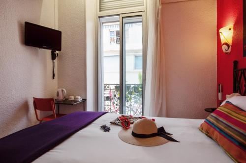 a hat sitting on top of a bed with a window at Hôtel Brimer Cannes in Cannes