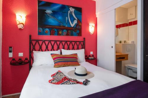 カンヌにあるホテル ブリメーラ カンヌの赤いベッドルーム(ベッド、帽子付)