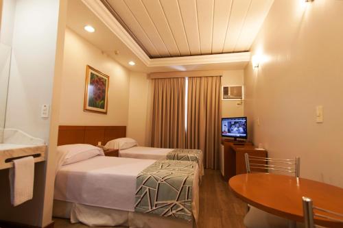 una camera d'albergo con due letti e una televisione di Di Giulio Hotel a São José dos Campos