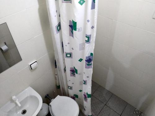y baño con aseo y cortina de ducha. en LOCAÇÃO P M Costa Esmeralda RUA 321, en Itapema
