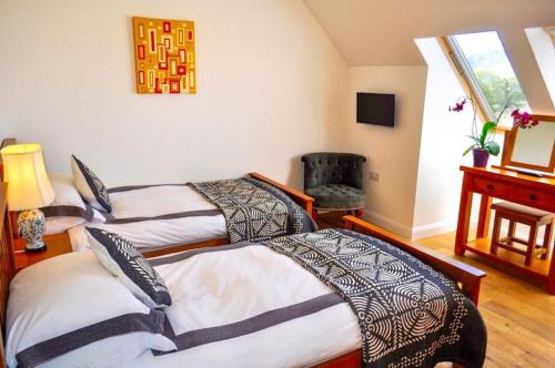1 dormitorio con 2 camas, escritorio y ventana en Lurach House, en Port Appin