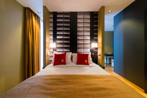 a bedroom with a large bed with red pillows at Hotel The Royal Snail in Namur